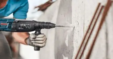 broca para concreto. Persona con un taladro en las manos y con guantes especiales taladrando, con una broca para concreto.