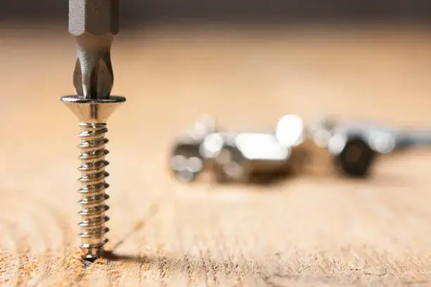 Tornillo introduciéndose en superficie de madera clara para ejemplificar diferencias clave entre tornillos para concreto vs tornillos para madera.