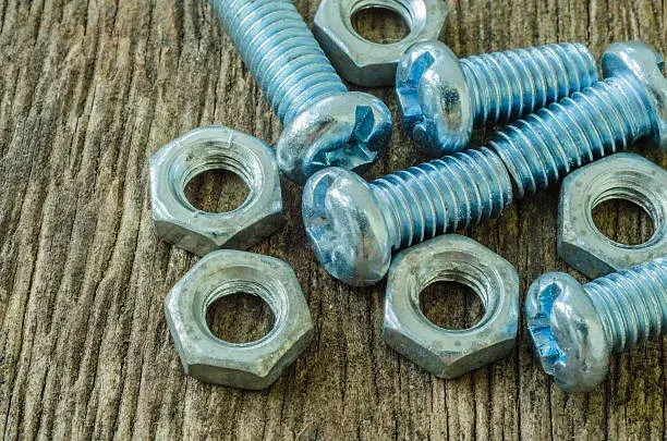 Tornillos de acero inoxidable brillantes dispuestos en superficie metálica para asegurar uniones firmes en distintos tipos de estructuras