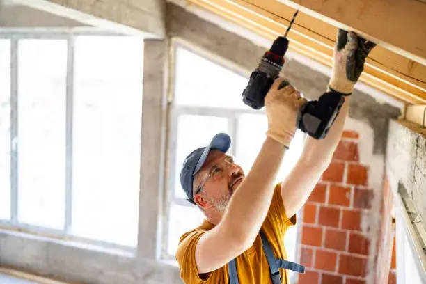 Hombre perforando una pared con un taladro profesional, mostrando precisión y control durante la operación, representando el uso eficiente de taladros en construcción y bricolaje.
