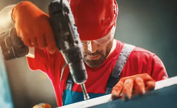 Hombre realizando un orificio en la pared con un taladro eléctrico, mostrando su potencia y control, ejemplificando la utilidad de taladros en trabajos de construcción y remodelación.